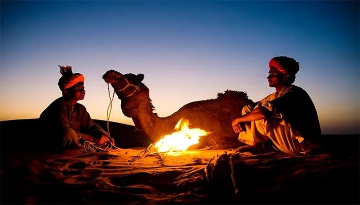 a man sitting next to a camel